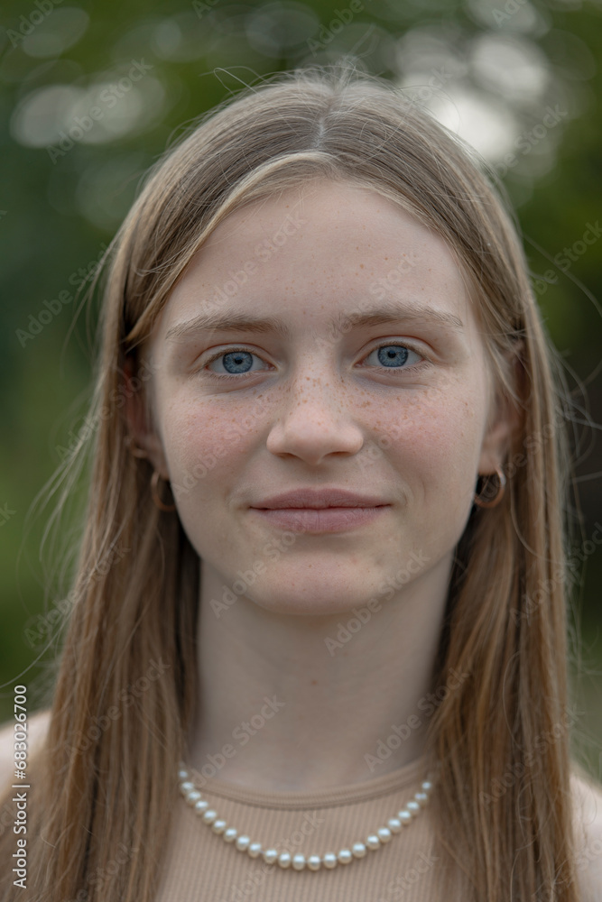 Portrait of a beautiful happy girl with blond hair and freckles looking at the camera and smiling charmingly, closeup, outdoors Portrait of a beautiful happy girl with blond hair and freckles looking at the camera and smiling charmingly, closeup, outdoors