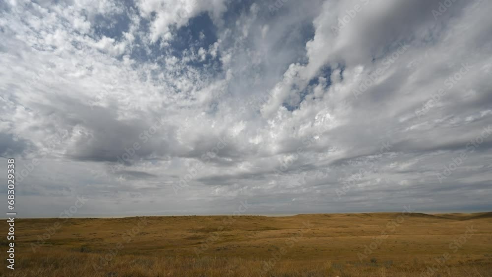 Time lapse of spectacular puffy white summer clouds moving towards the viewer over a dry prairie setting. Sunlight moves across the dry grass highlighting the small hills.
Time lapse of spectacular puffy white summer clouds moving towards the viewer over a dry prairie setting. Sunlight moves across the dry grass highlighting the small hills.