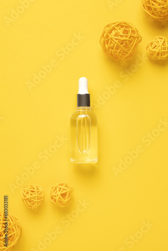 Glass dropper bottle with cosmetic oil, essential or serum on yellow background. Herbal homeopathic products. Natural organic spa cosmetics.