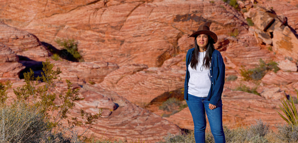 Fototapeta premium Young woman in a western style outfit exploring the amazing Red Rock Canyon in Nevada - travel photography