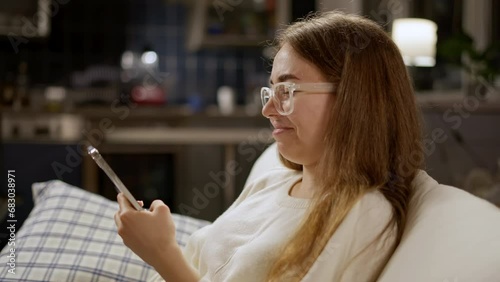 Teen girl with smartphone laughing hard, loud laugh, burst out laughing  with funny meme. Giggling young woman in glasses holding smartphone. Funny humor comedy chatting online