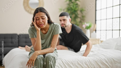 Beautiful couple supporting each other in love, hugging seriously while sitting on bedroom bed amidst the sadness, embodying a strong bond indoors. photo