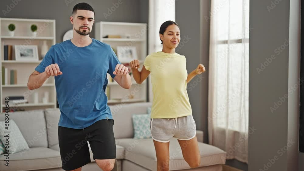 Beautiful, athletic couple expressing love through dancing together at home, turning living room into indoor fitness house for a healthy, sporty lifestyle Beautiful, athletic couple expressing love through dancing together at home, turning living room into indoor fitness house for a healthy, sporty lifestyle