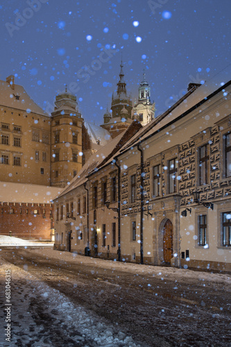 Wawel castle and Wawel cathedral from kanonicza street during snowfall in the night, Krakow, Poland