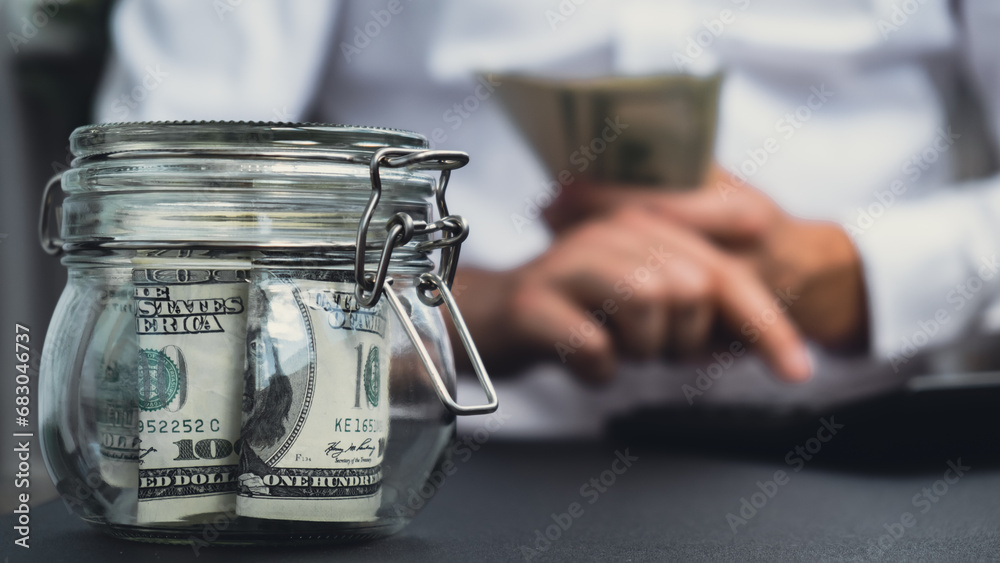 Fototapeta premium Man hands counting expenses banknotes of dollar cash on calculator. Close up of hands unrecognizable Businessman. Save up budget investment concept. American bucks fund savings