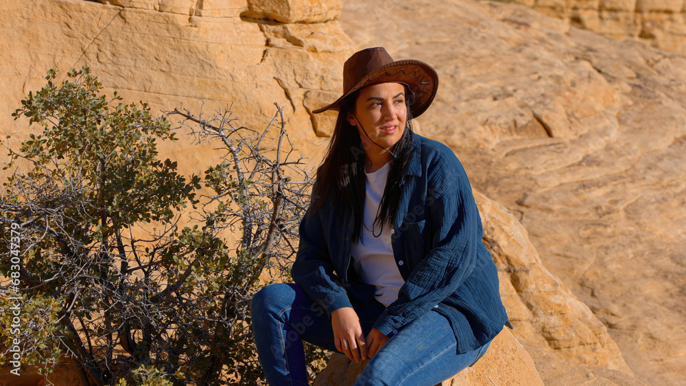 Naklejka premium Young woman in western outfit enjoying the tranquility in a canyon of the Nevada desert - travel photography