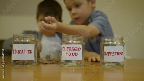 Budgeting and investment in education. Early financial literacy. Boy puts coind in the jar for education. High quality 4k footage photo