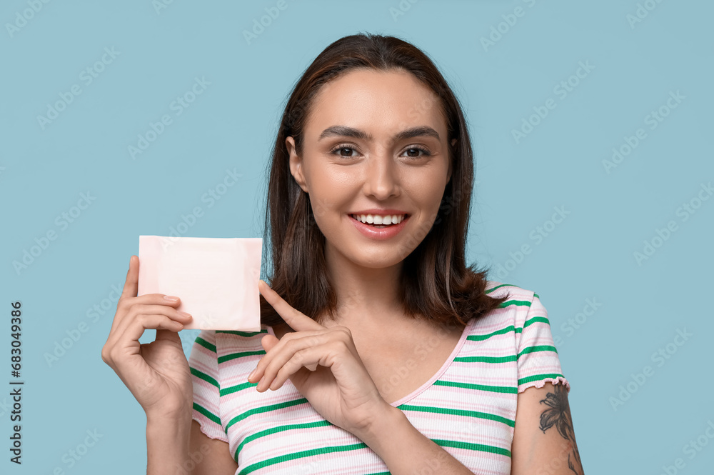 Beautiful young woman with menstrual pad on blue background Beautiful young woman with menstrual pad on blue background