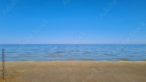 Clear blue sky over the sea and the sandy shore of the beach