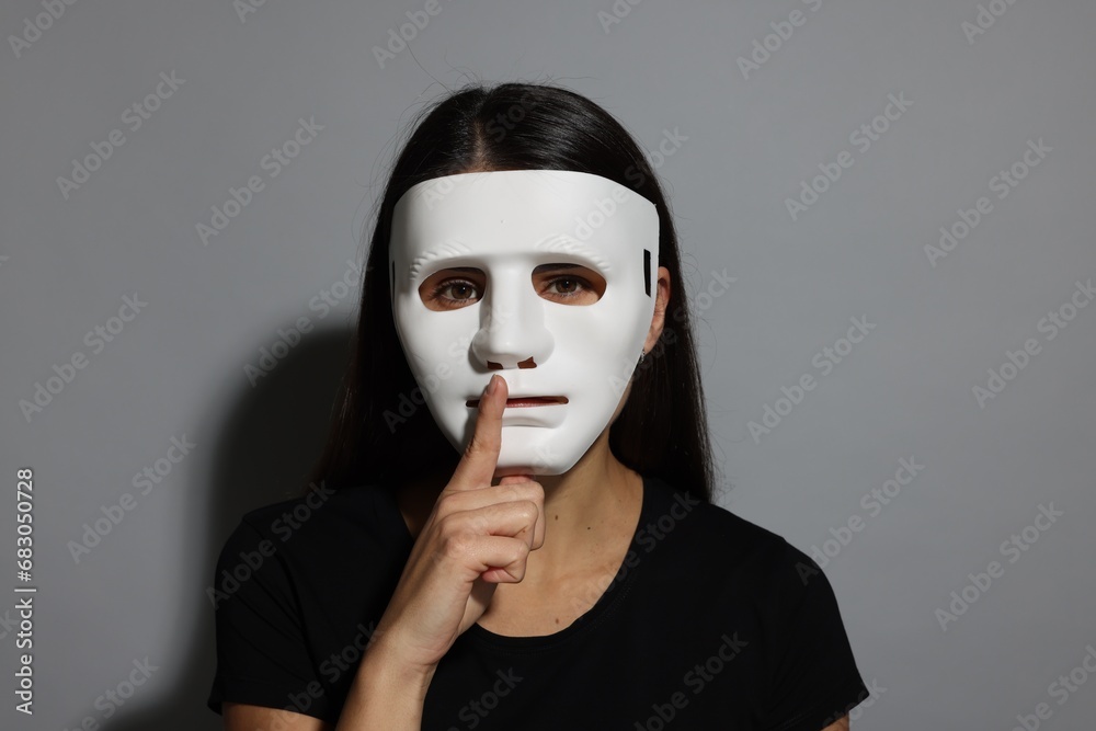 Multiple personality concept. Woman in mask on grey background Multiple personality concept. Woman in mask on grey background