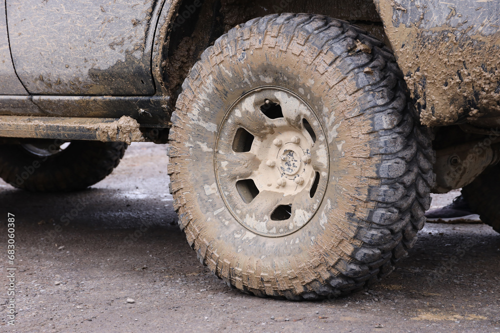Wheel closeup in a countryside landscape with a mud road. Off-road 4x4 suv automobile with ditry body after drive in muddy road area Wheel closeup in a countryside landscape with a mud road. Off-road 4x4 suv automobile with ditry body after drive in muddy road area