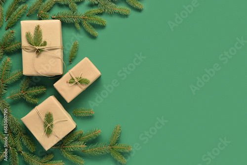 Gift boxes with pine branches on green background.
