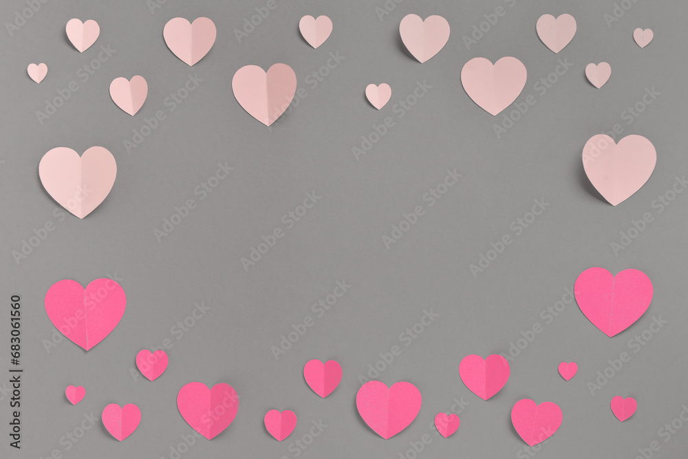Frame shaped romantic composition with pink paper hearts on grey background. St. Valentine's Day.