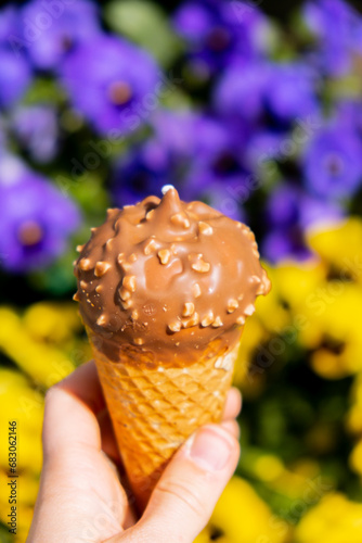 Female hand holding delicious american vanilla chocolate ice cream. Tasty homemade icecream Gelato in the waffle cone. Gluten free vegan dairy free