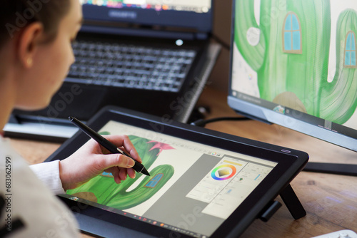 Young woman drawing on a digital tablet. Girl working as graphic designer. Girl drawing on a digital drawing board