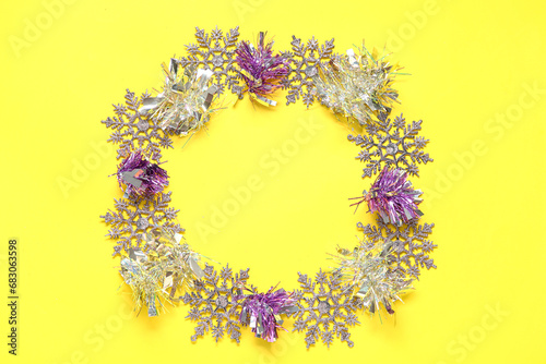Frame made of Christmas tinsel and snowflakes on yellow background