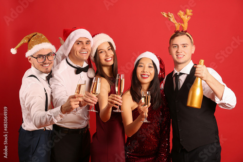 Group of friends with champagne on red background. New Year celebration