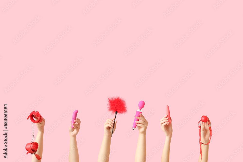 Female hands with different sex toys on pink background Female hands with different sex toys on pink background