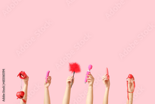 Female hands with different sex toys on pink background