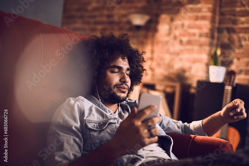 Carefree young man with eyes closed listening to music at home photo