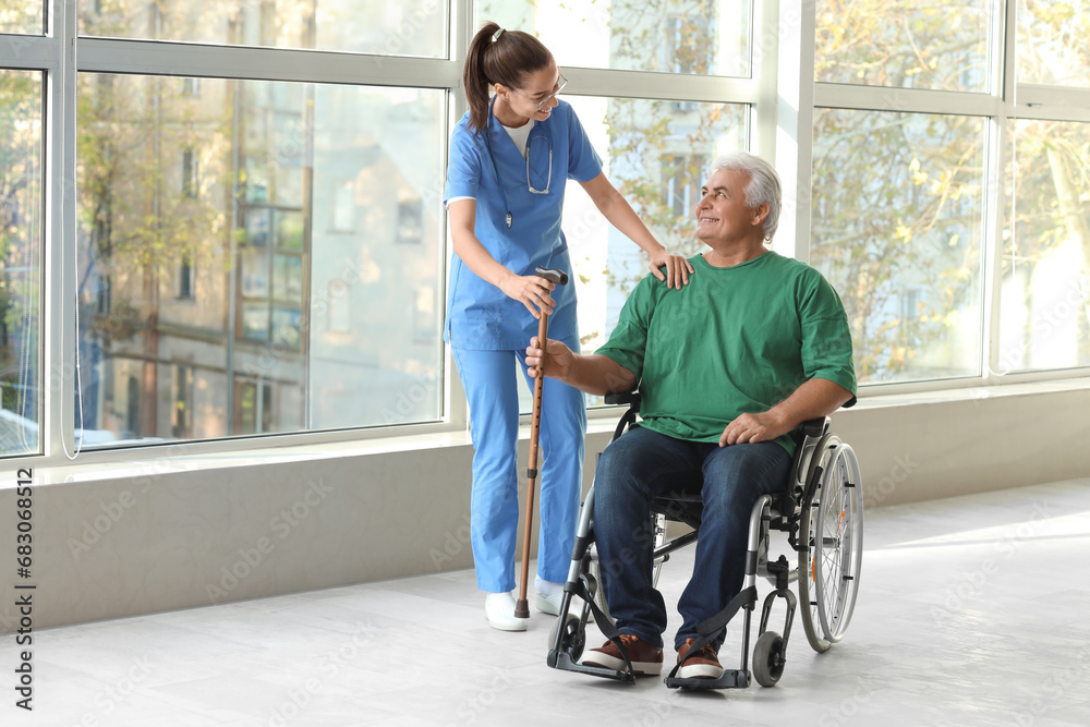 Senior man in wheelchair with stick and nurse at hospital Senior man in wheelchair with stick and nurse at hospital