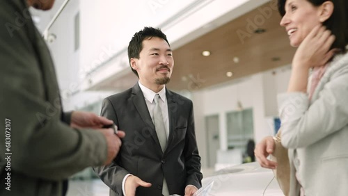 Salesman bringing new car keys to couple at the dealership