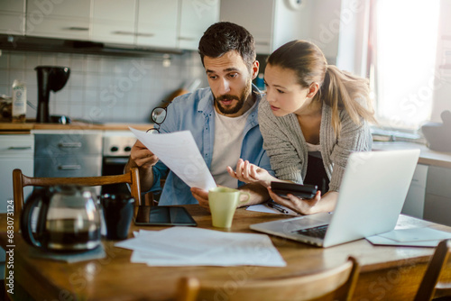 Young couple reading bad financial report having financial debt at home photo