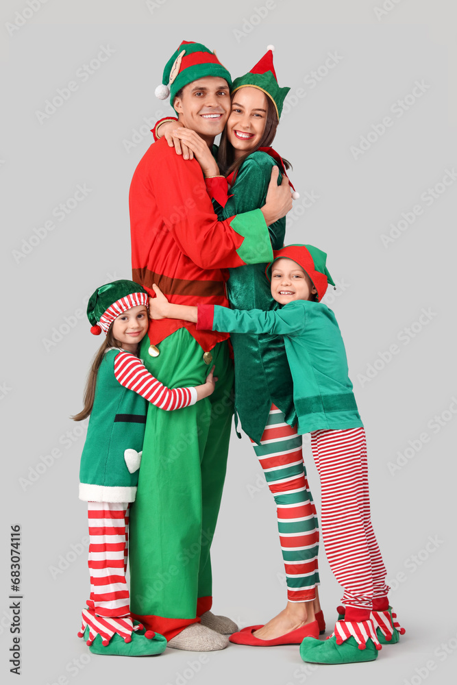 Obraz premium Happy family in elf's costumes hugging on grey background