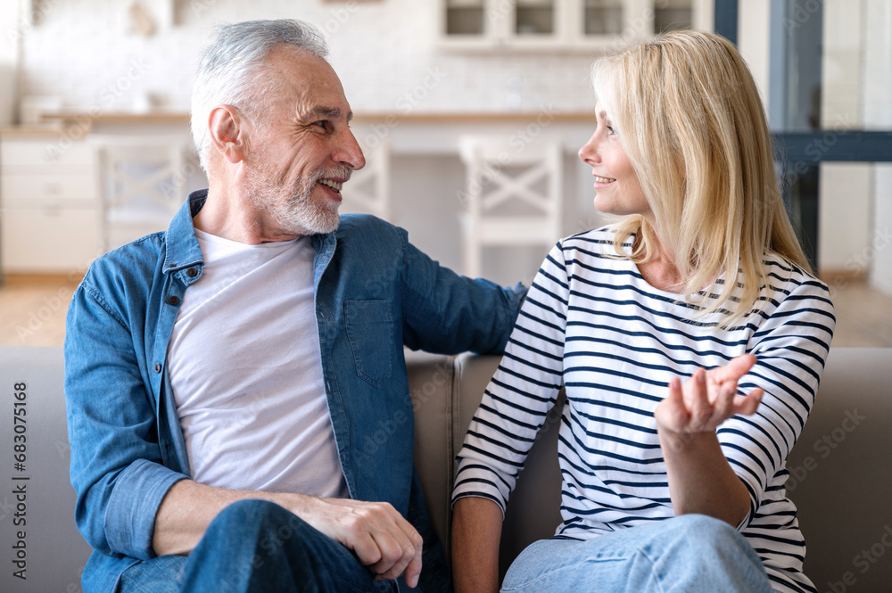 Mature man and woman talking and relaxing on couch in dining room Mature man and woman talking and relaxing on couch in dining room