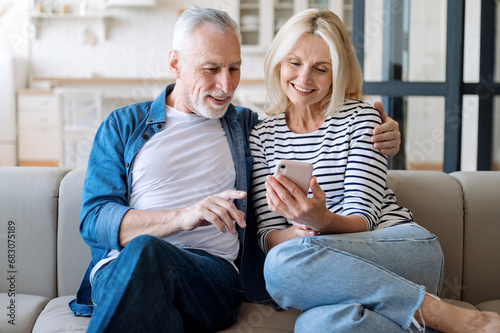 Middle aged smiling man and woman using smartphone for online shopping