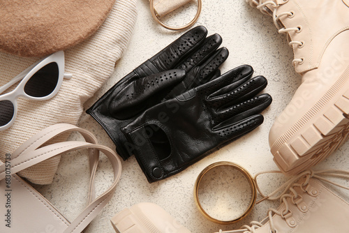 Composition with black leather gloves, shoes and accessories on light background, closeup