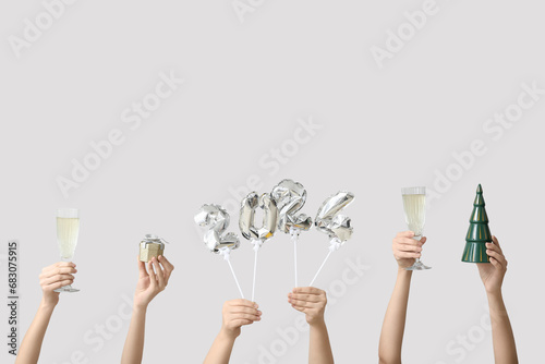 Female hands with figure 2024 made of balloons and glasses of champagne on white background photo