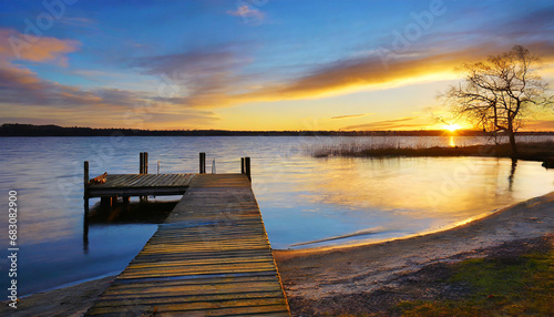 sunset over the beach with a dock by a lake