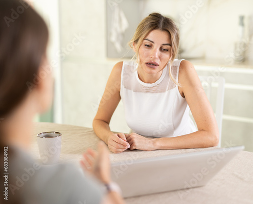 Fotografie Smiling middle-aged female manager talking about work to another woman in the ki