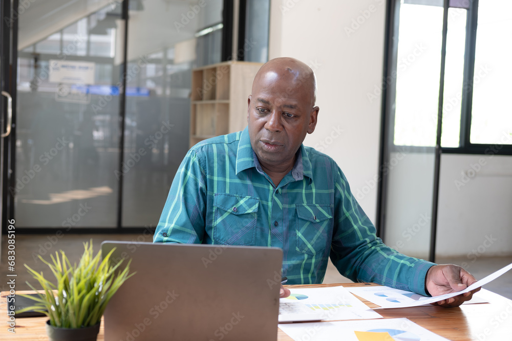 Fototapeta premium Young business man working at home with laptop and papers on desk