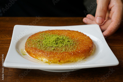 hand holding a plate with kunefe