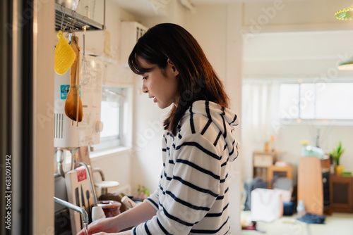 団地の台所で家事をする女性
