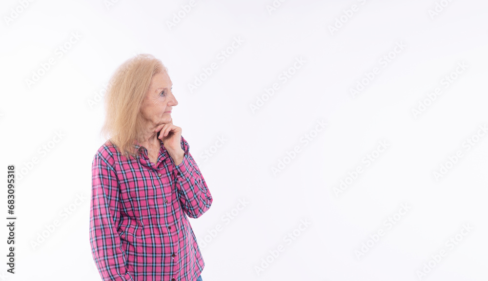Positive confident 70s healthy grandmother holding finger under thinking get idea looking copy space over isolated white background. Thoughtful elderly aged woman casual long sleeve looking up empty.