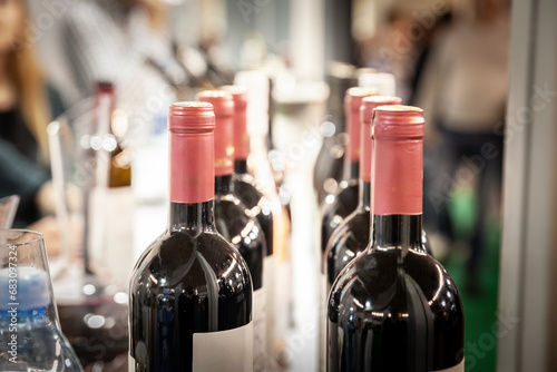 Selective blur on bottlenecks of bottles of red wine on display, ready for wine tasting, on a row, stacked in line. photo