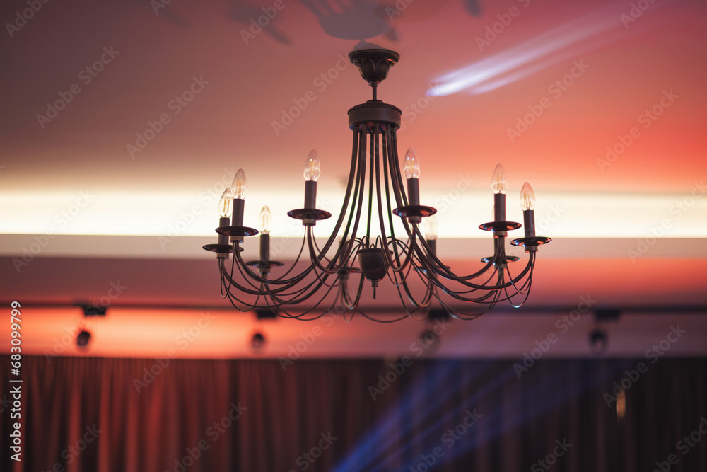 Turning the lights on and off on a beautiful iron candelabra chandelier in restaurant. Traditional, ancient style candelabra and light illumination. 