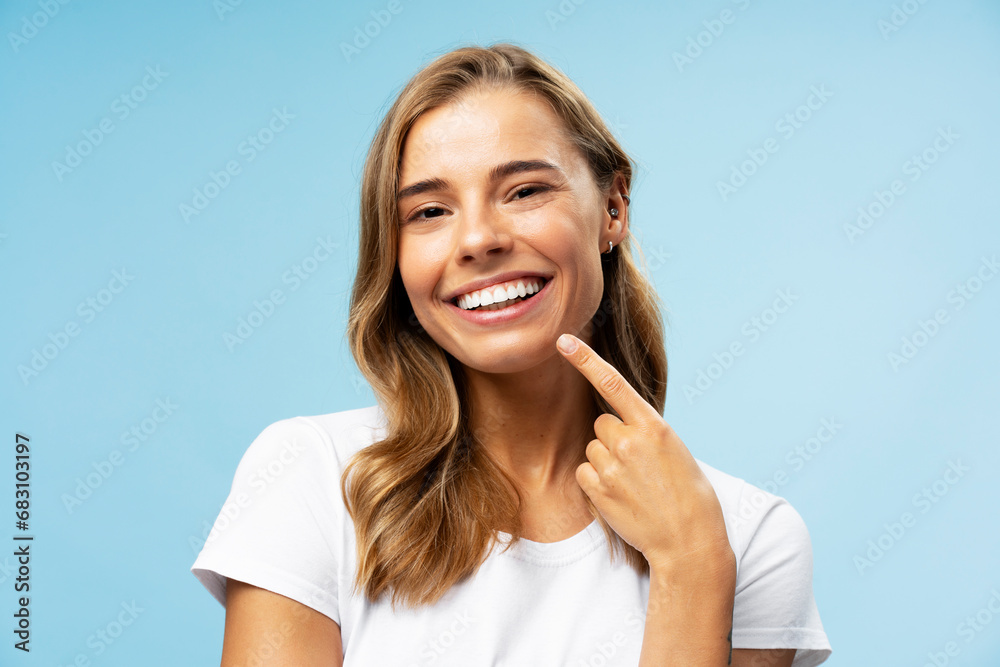 Portrait of smiling beautiful woman pointing finger at her teeth looking at camera standing Portrait of smiling beautiful woman pointing finger at her teeth looking at camera standing