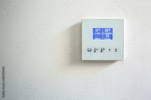 Modern thermostat mounted on white wall at home photo