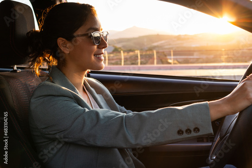 Happy businesswoman in sunglasses driving car