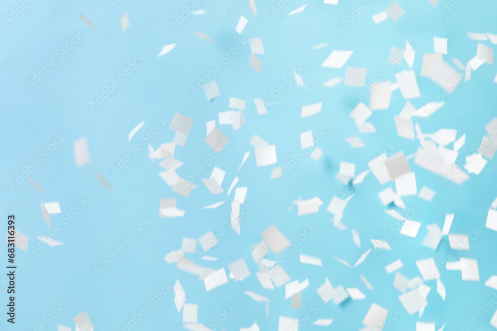 White confetti falling down on light blue background