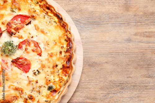 Tasty quiche with tomatoes and cheese on wooden table, top view. Space for text