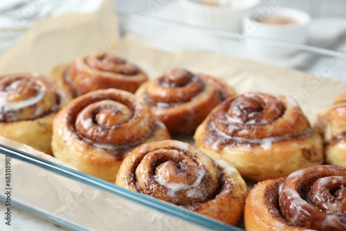 Baking dish with tasty cinnamon rolls on white table, closeup