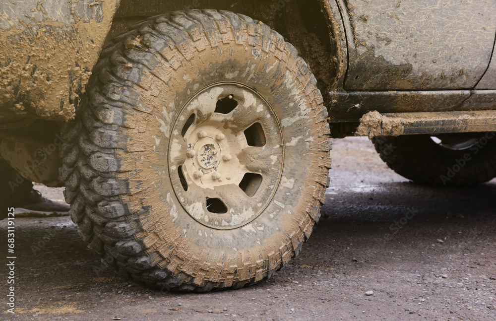 Wheel closeup in a countryside landscape with a mud road. Off-road 4x4 suv automobile with ditry body after drive in muddy road area Wheel closeup in a countryside landscape with a mud road. Off-road 4x4 suv automobile with ditry body after drive in muddy road area