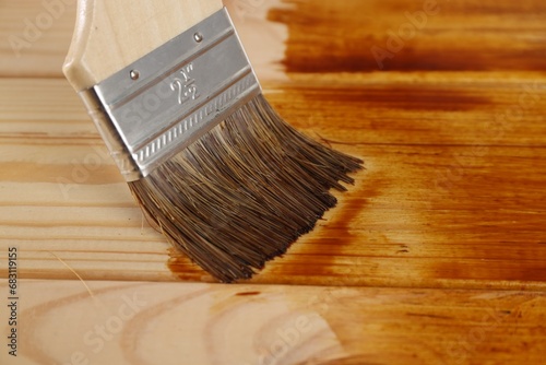 Applying wood stain on wooden surface, closeup