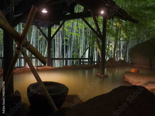 Traditional Japanese Rotenburo onsen hot spring outdoor bath in Illuminated bamboo grove in the night