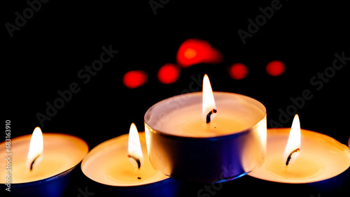 Three burning candles on black background
